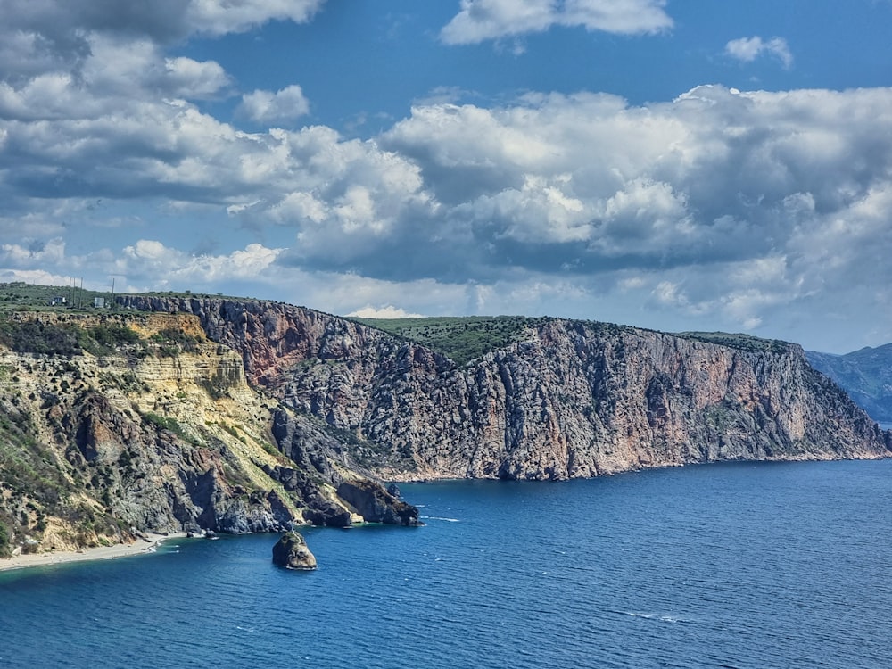 a rocky cliff next to a body of water