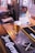 A pint of beer with a frothy head is placed on a metal drip tray at a bar counter. Behind the glass, there is a beer tap with a graphic design featuring a skull. Bar mats with distinct logos are visible on the wooden counter, adding to the pub atmosphere.
