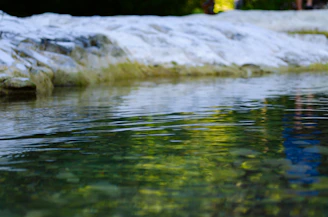 A quiet spot by calm water with smooth stones and delicate ripples.