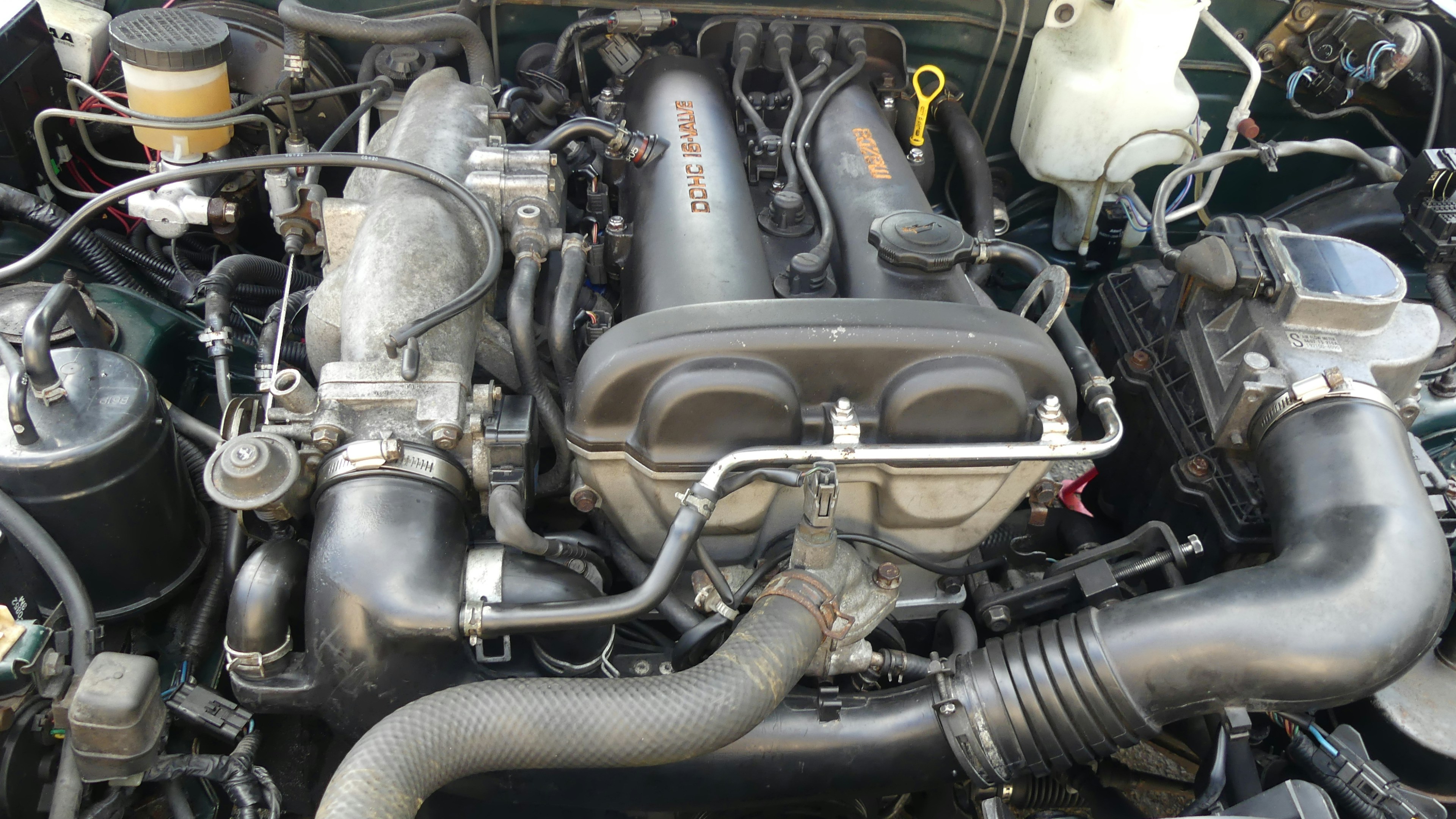 Mechanic performing an engine oil change on a compact SUV similar to a 2017 Nissan Rogue