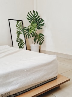 A minimalist bedroom showcasing a tall standing mirror with a thin metal frame leaning against the wall.