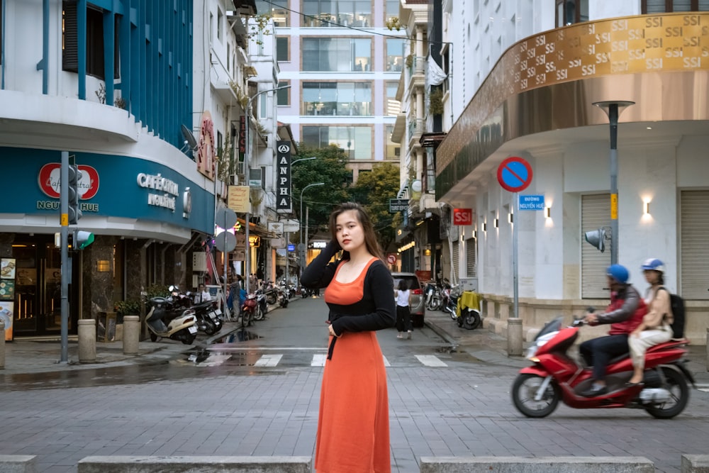 a person in a red dress standing in the middle of a street