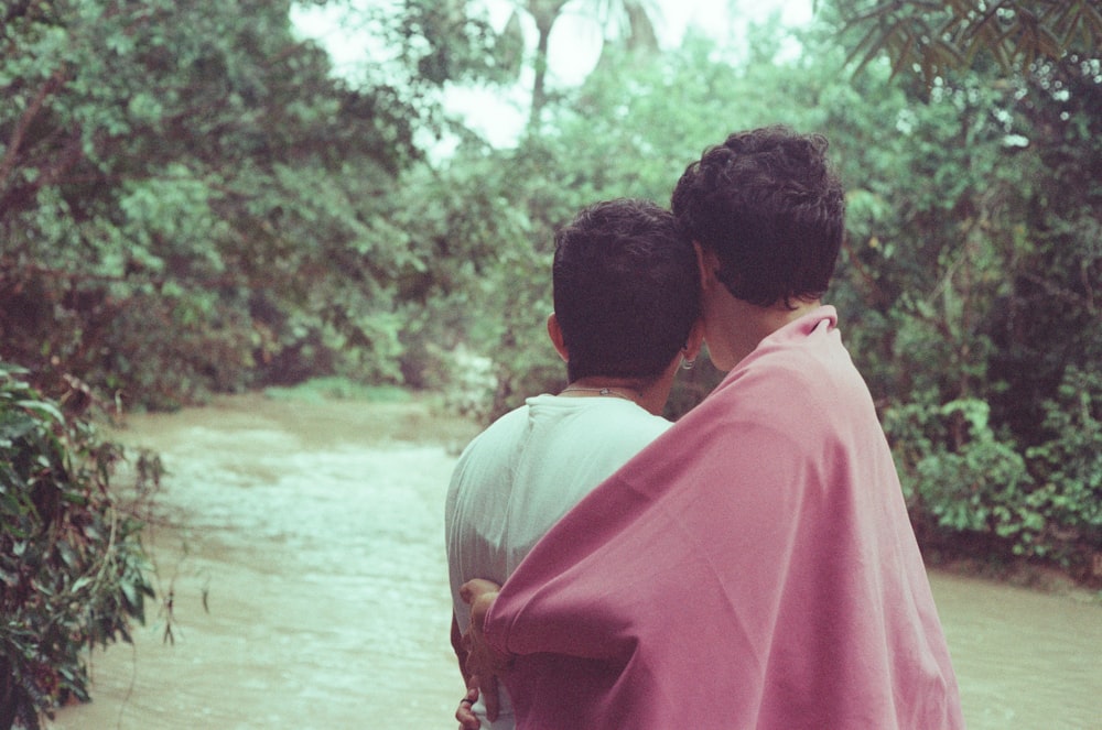 two people standing in front of a river