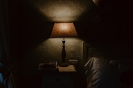 A bedside lamp with a soft, inviting glow next to a stack of books.