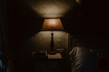 Close-up of soft linens and a bedside lamp casting a warm glow in a boutique hotel room.