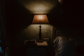 A bedside lamp with a soft, inviting glow next to a stack of books.