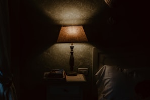 A bedroom bedside table featuring a sleek lamp and a stack of favorite books.