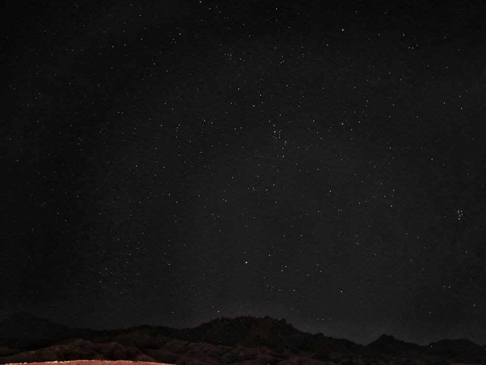 a starry night sky over a rocky mountain