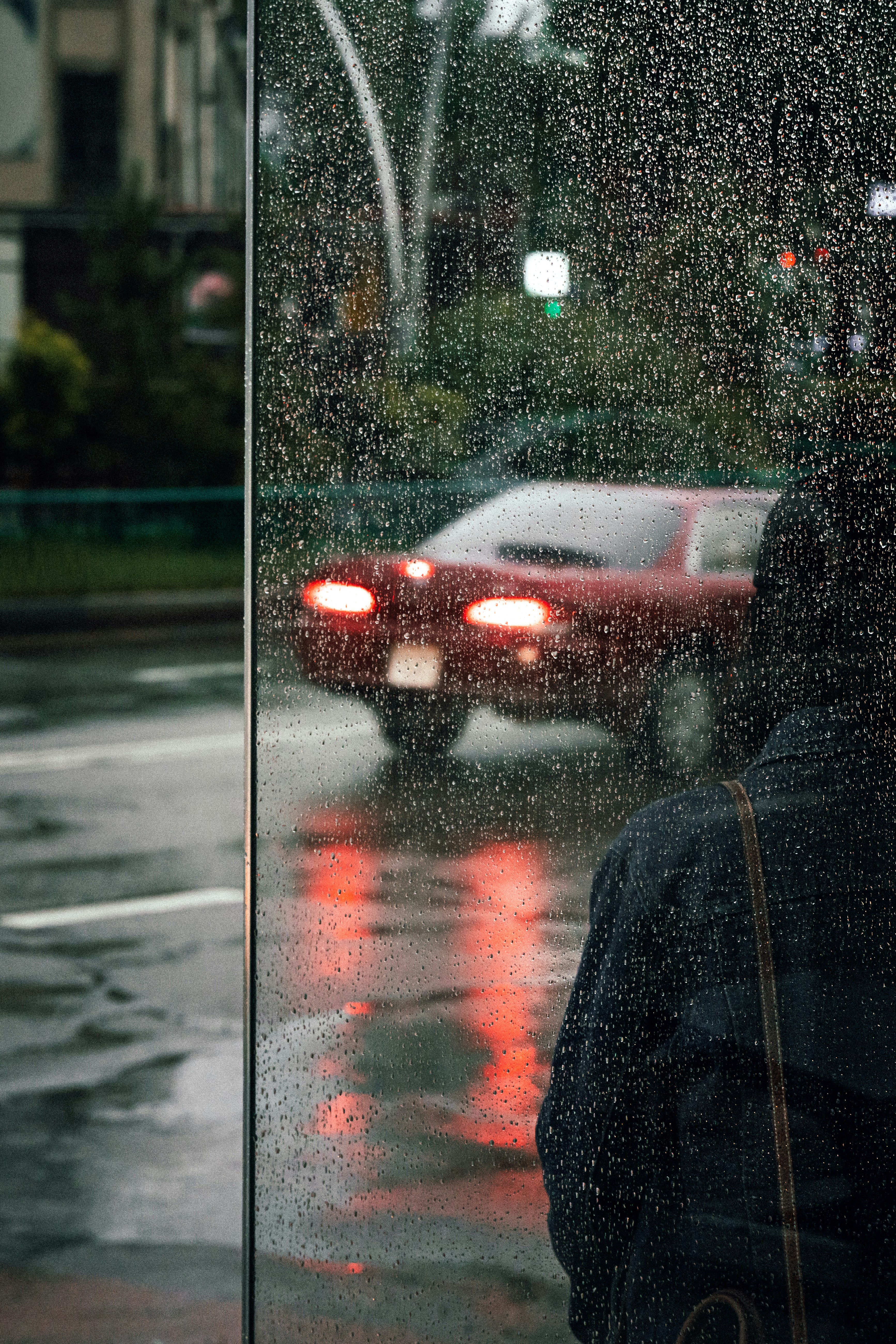 a person standing in front of a car on a rainy day