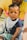 A baby with curly hair sits on someone's lap, wearing a navy blue shirt and plaid shorts. A white bib with text is around the baby's neck, and a stuffed toy is held by the baby. The person holding the baby is wearing a yellow shirt with a visible logo.