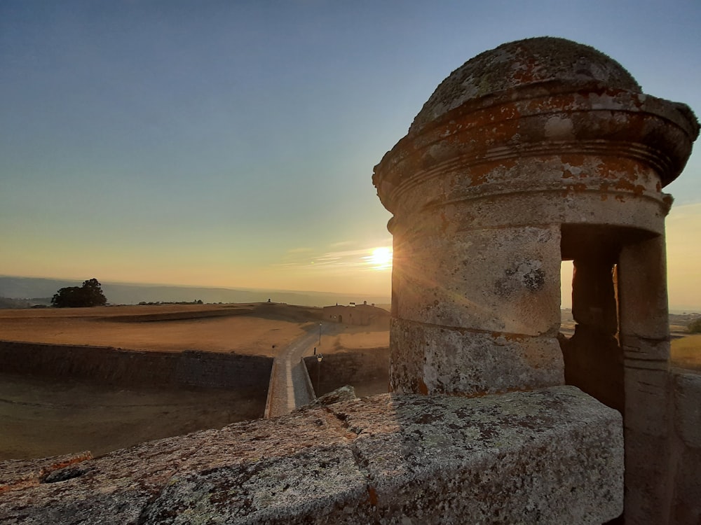 a stone structure with a sunset in the background