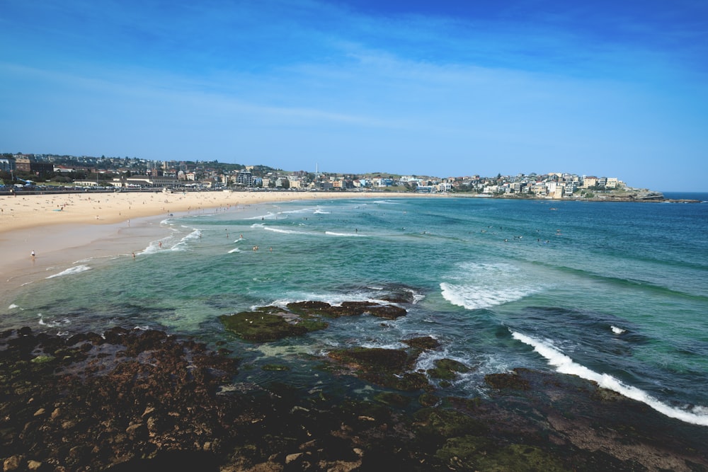 a beach with waves and buildings in the background with Bondi Beach in the background