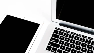 a black and white photo of a laptop and a keyboard