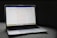 A MacBook Pro laptop displaying a webpage with a soft gray couch as a backdrop. The screen shows a website with text in the center, including a passage labeled 'Do Not Worry'. The laptop's backlit keyboard and touchpad are visible, and the bottom screen displays several application icons in the dock.