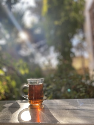 A sleek glass cup filled with iced tea, catching the sunlight beautifully