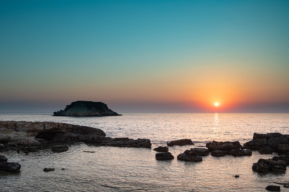 a rocky beach with the sun setting