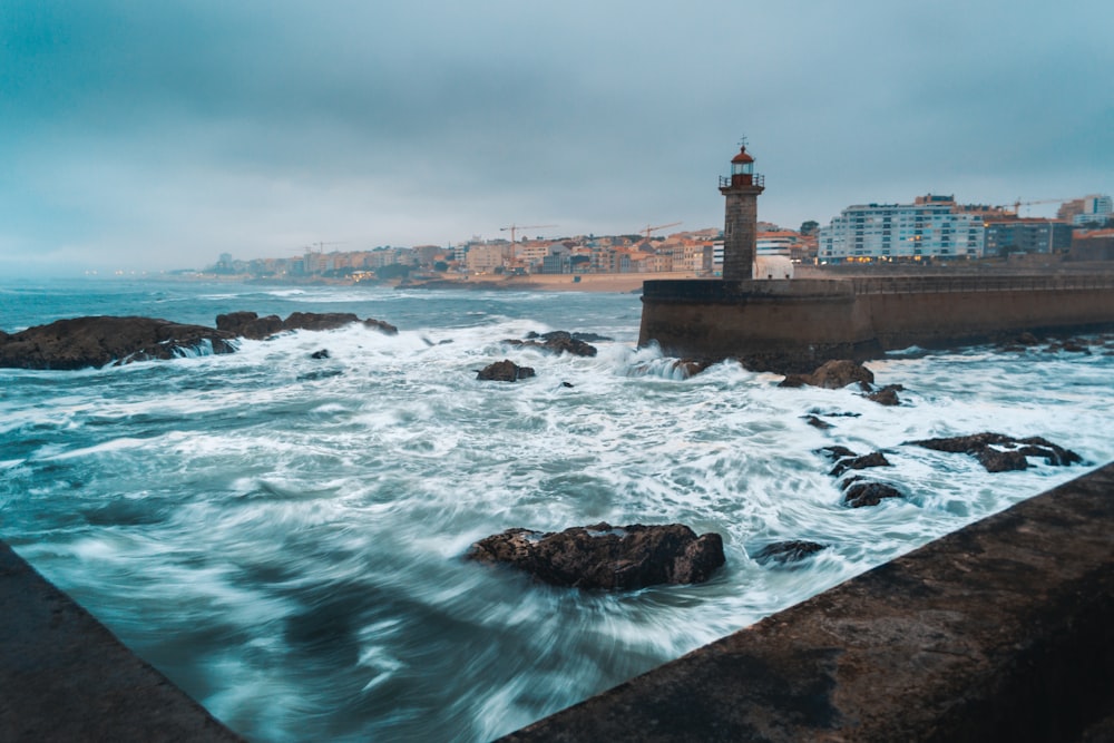 a rocky beach with a lighthouse in the background