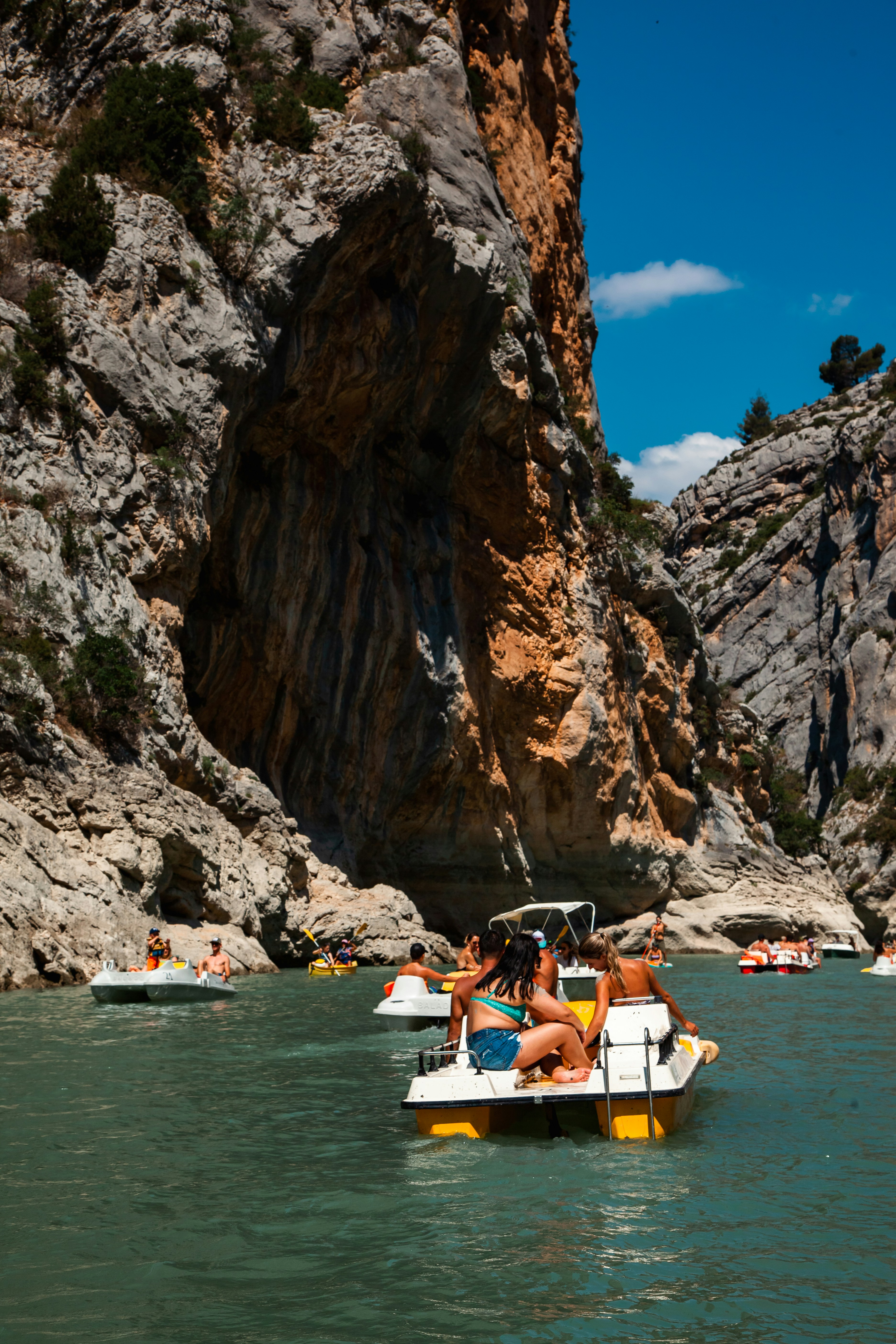 Personas en un bote en un cuerpo de agua junto a un acantilado