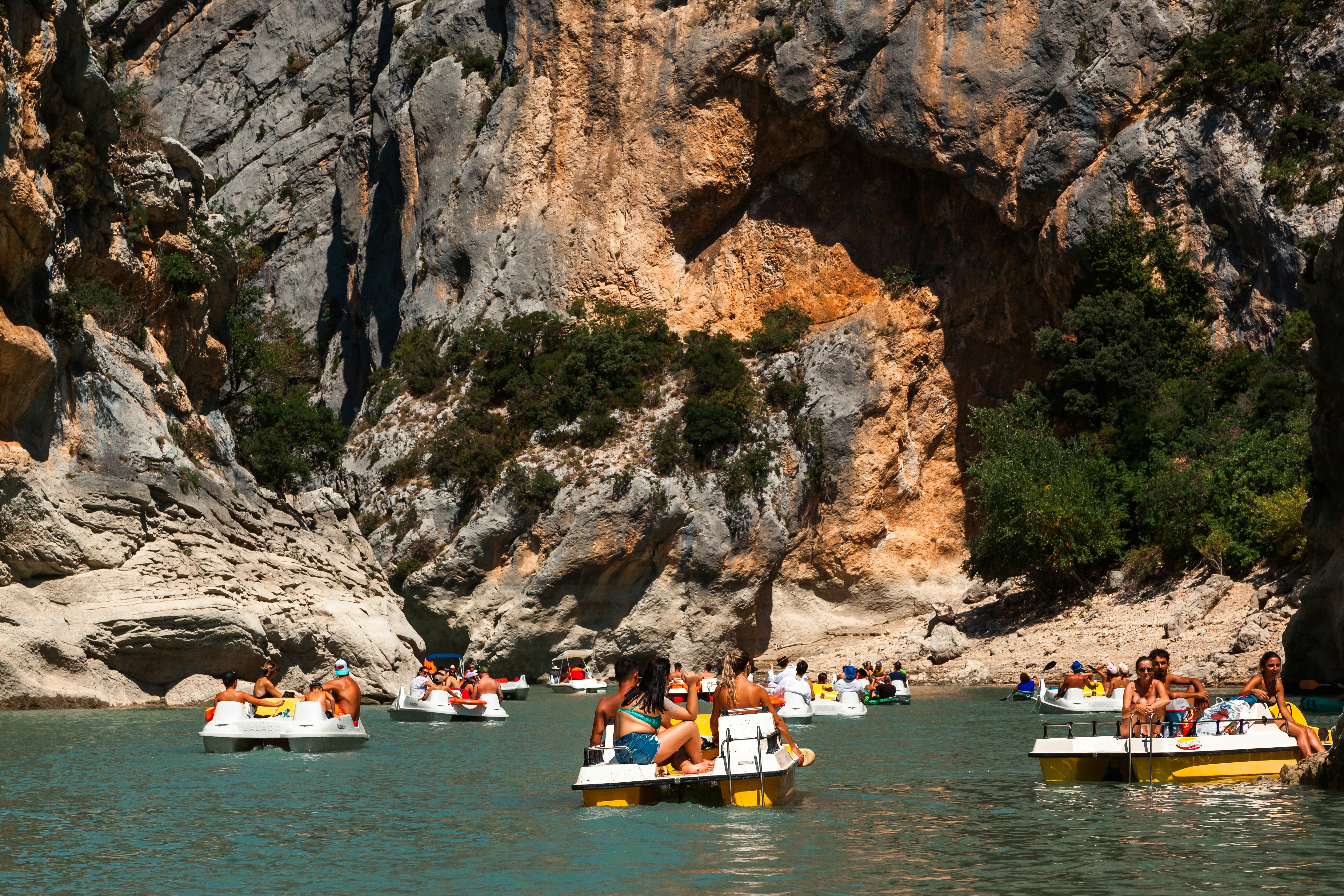 Un grupo de personas en botes en un cuerpo de agua junto a un acantilado rocoso