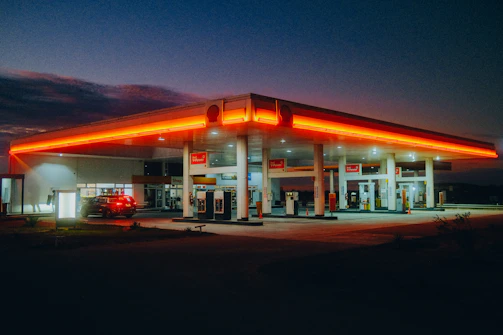 A sleek, modern gas station at dusk with warm lighting and a clear sky.