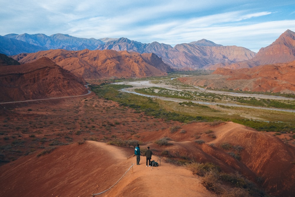 a group of people walking on a dirt road in a mountainous region