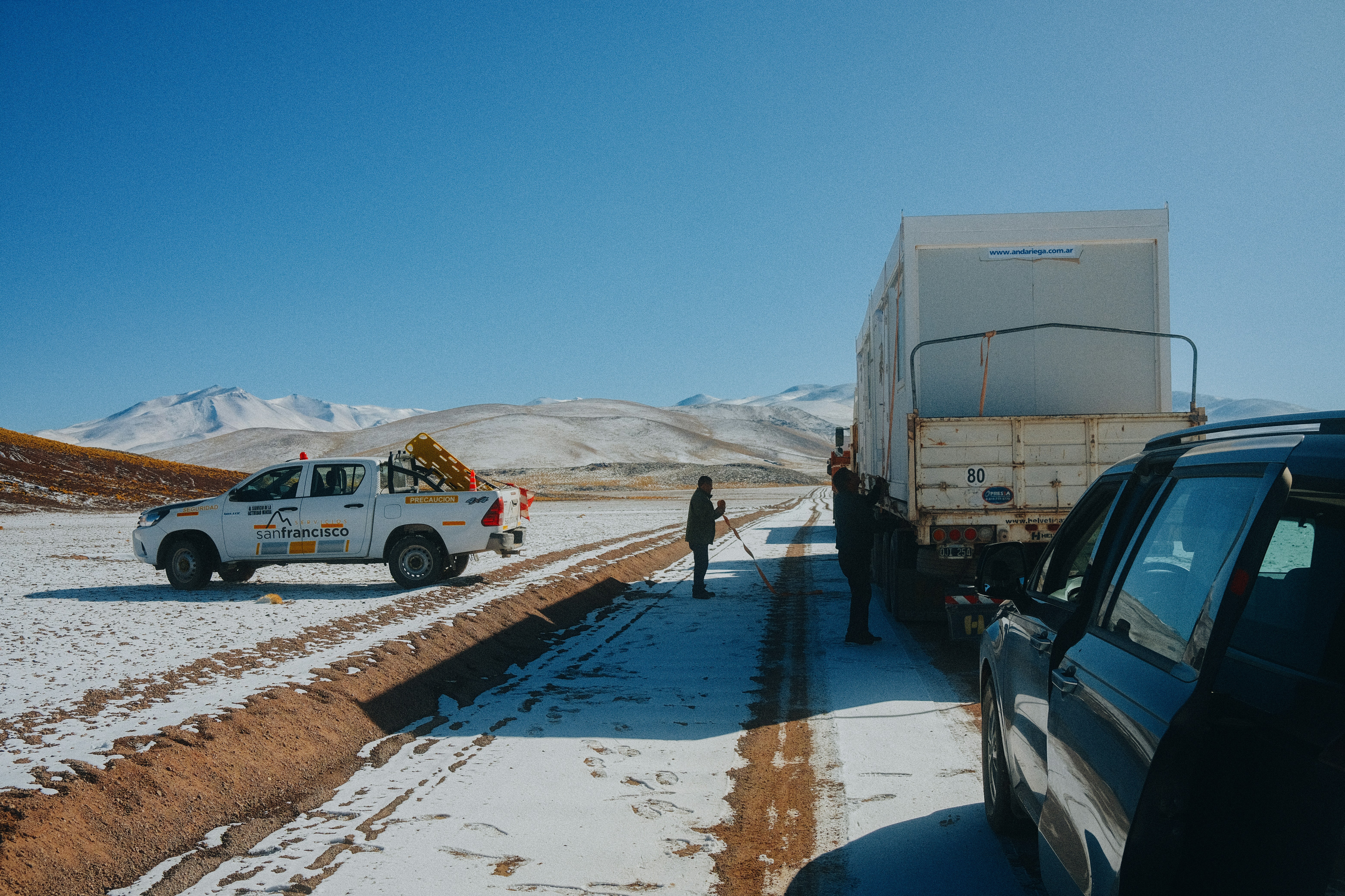 a group of people standing next to a truck in the snow