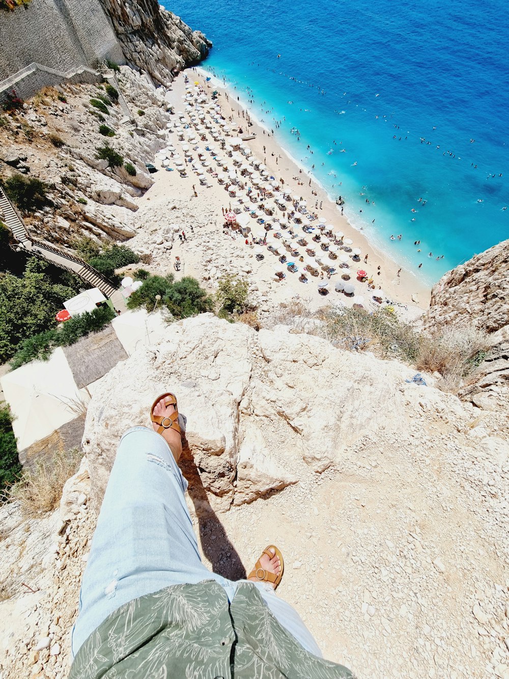 a person lying on a rock overlooking a beach