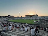 Dynamic shot of a football creator filming a trick shot on a stadium pitch at dusk.