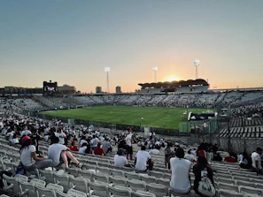 Dynamic shot of a football creator filming a trick shot on a stadium pitch at dusk.