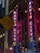 Neon signs for Radio City Music Hall are illuminated on a tall building. A yellow sign in the foreground notes a recessed crosswalk on 6 Ave. Additional street signs indicate directions and parking information for W 50 St.