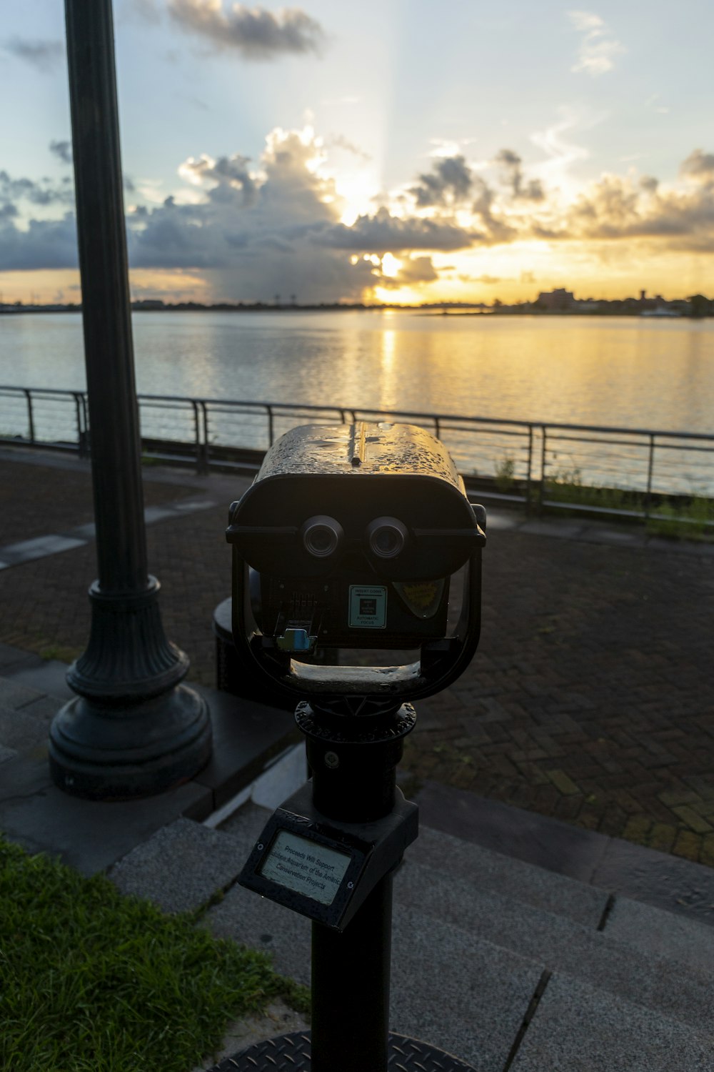 a metal object with a face on it by a body of water