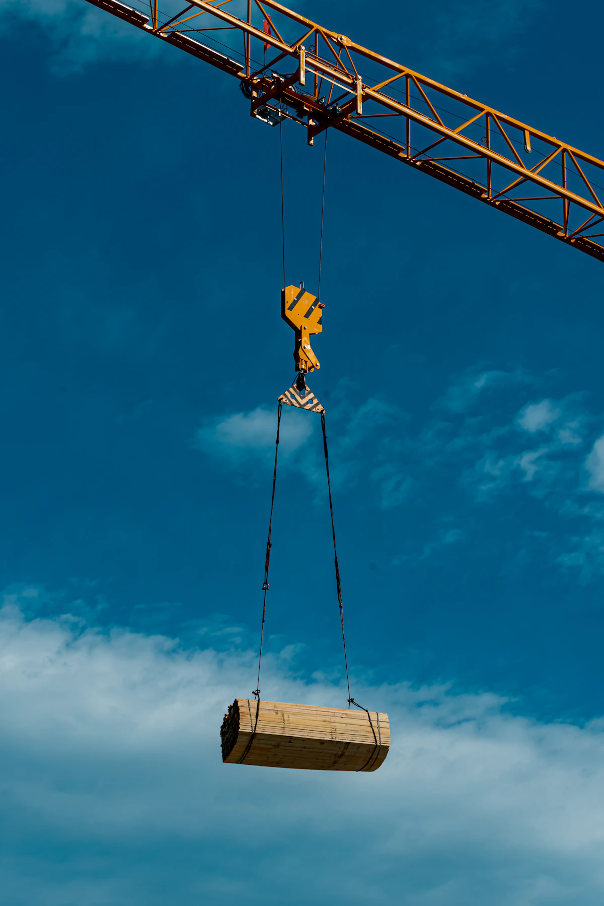 Mobile crane lifting a bundle of building materials at an active construction site