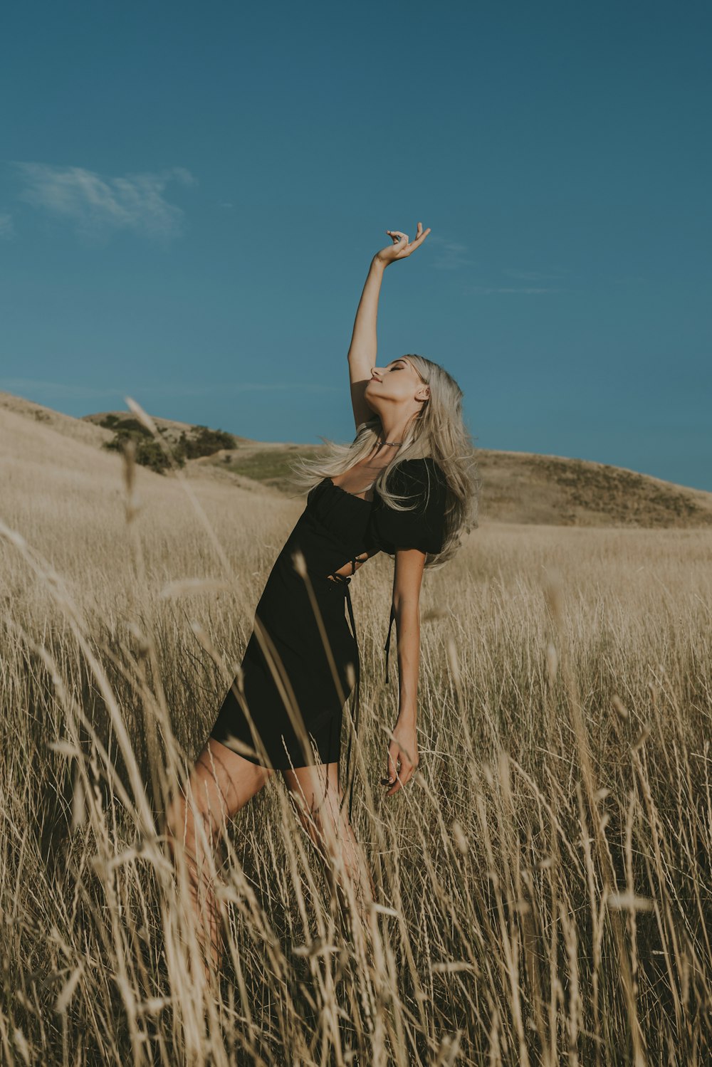 a man standing in a field of tall grass with his arms up