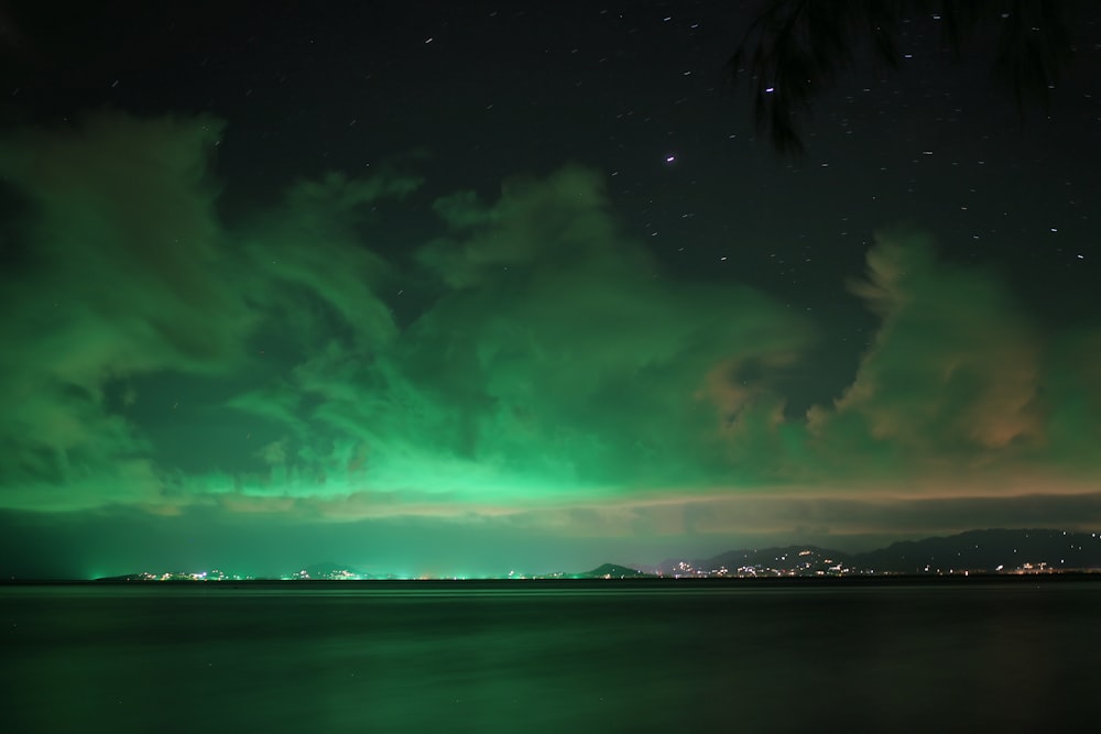 a green and purple sky over a body of water