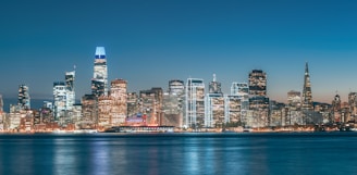 A vibrant city skyline at dusk with illuminated buildings.