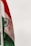 An Indian flag featuring horizontal tricolors of deep saffron, white, and India green with the blue Ashoka Chakra in the center. The flag is attached to a flagpole against a light sky.