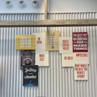 A collection of motivational and inspirational posters arranged on a corrugated metal wall. The posters feature phrases such as 'BE OPEN', 'MOVE FAST', 'BE BOLD', and 'BUILD SOCIAL VALUE' in bold typography. The display includes a stencil-style graphic of a wrench and other elements that convey a tech and innovation theme.