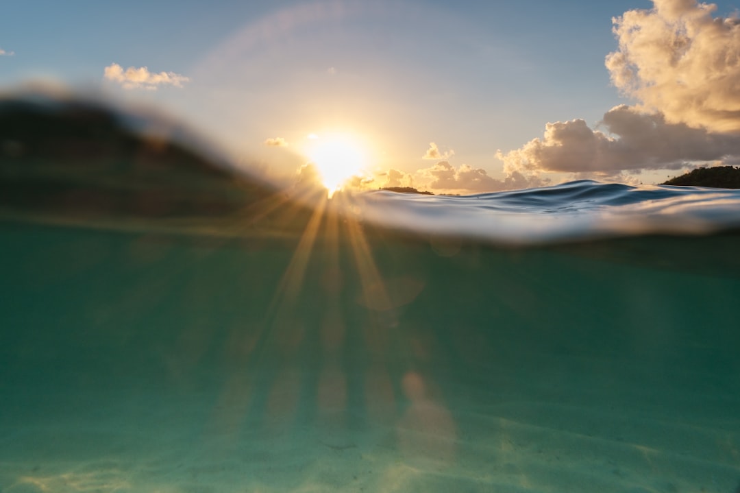 a body of water with the sun setting,