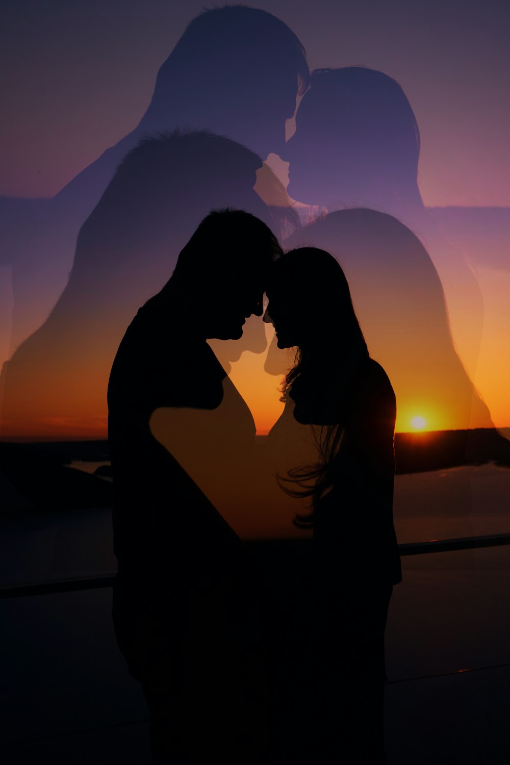 a silhouette of a man and woman kissing in front of a sunset