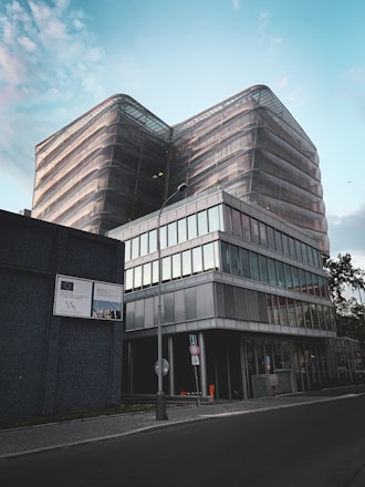 A modern office building with a 'For Sale' sign in front.