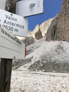 A rustic hiking trail signpost against a backdrop of towering Colorado peaks.