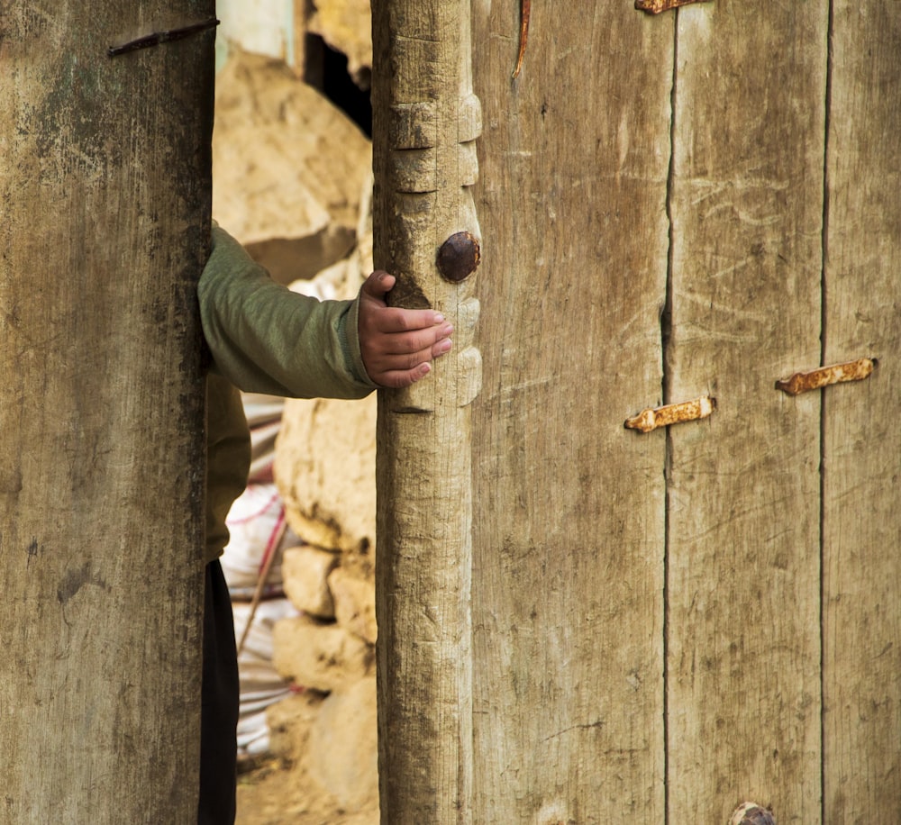 uma pessoa segurando um buraco em uma parede de madeira