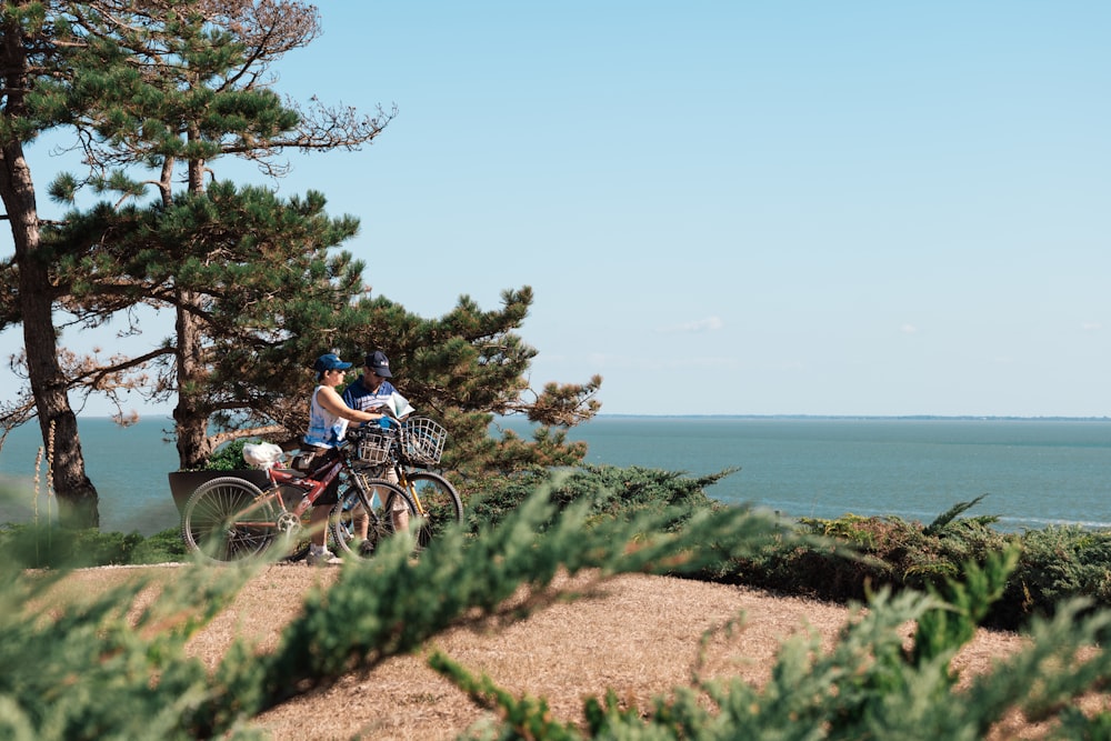 a couple riding bikes on a trail by the water