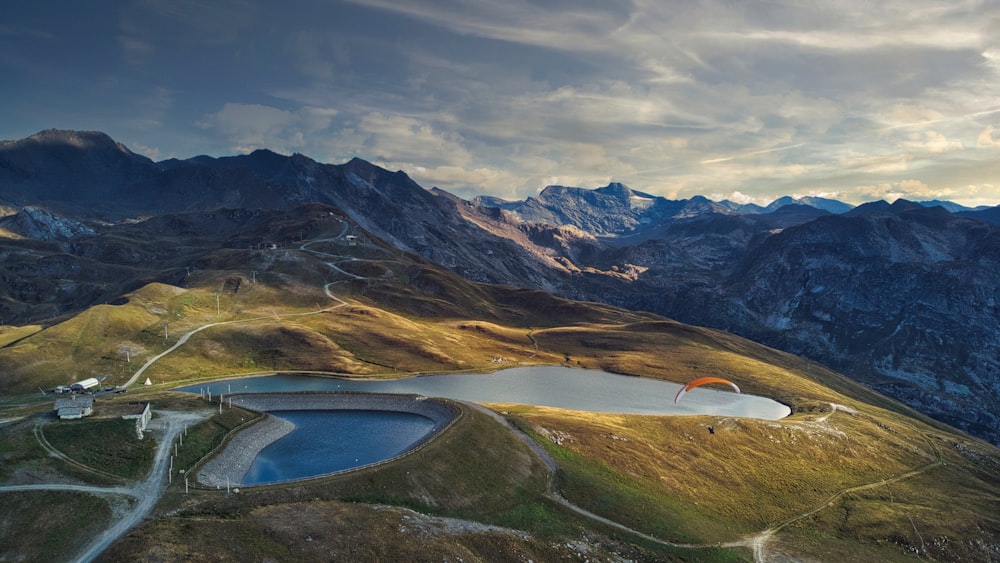 a person parachuting over a lake in a mountainous region