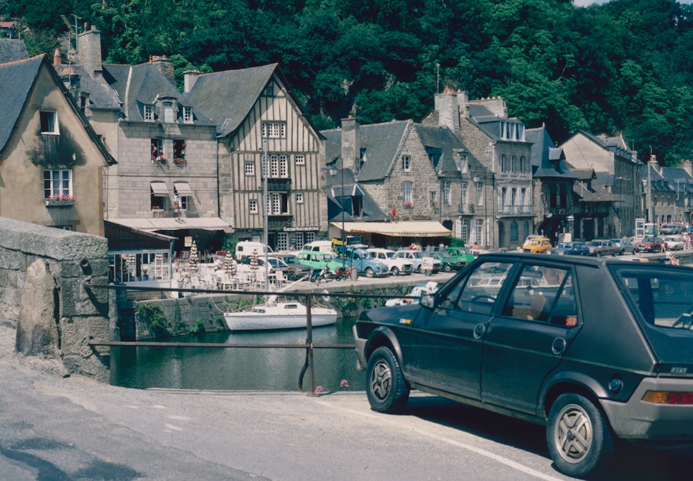 a car parked on the side of a road with a body of water and houses on the side