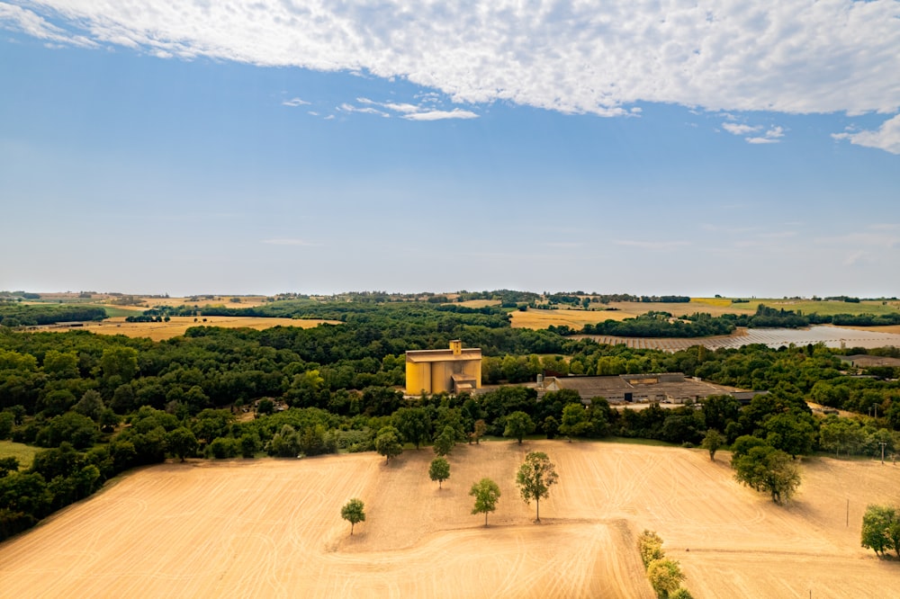 a large field with trees and a building in the distance