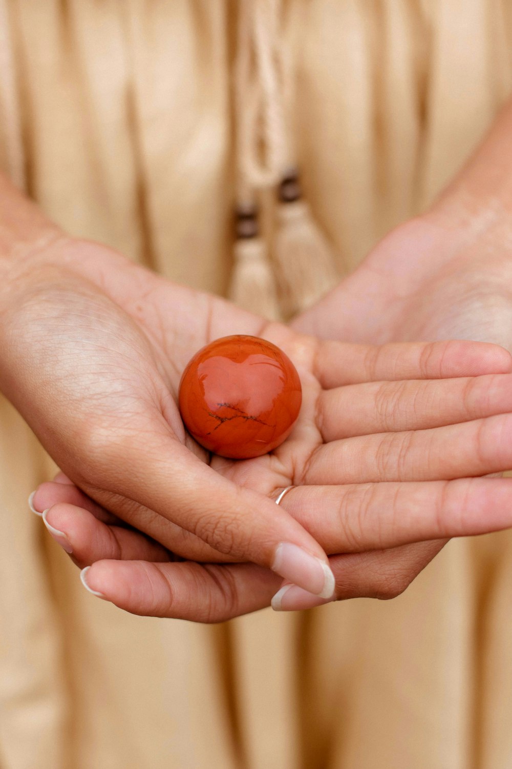 a hand holding a small orange ball