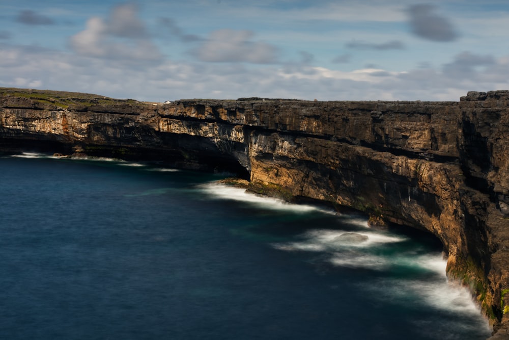 a cliff side with a body of water below