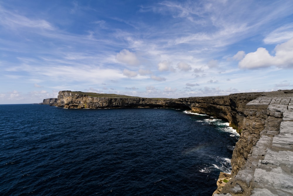 a rocky cliff next to a body of water