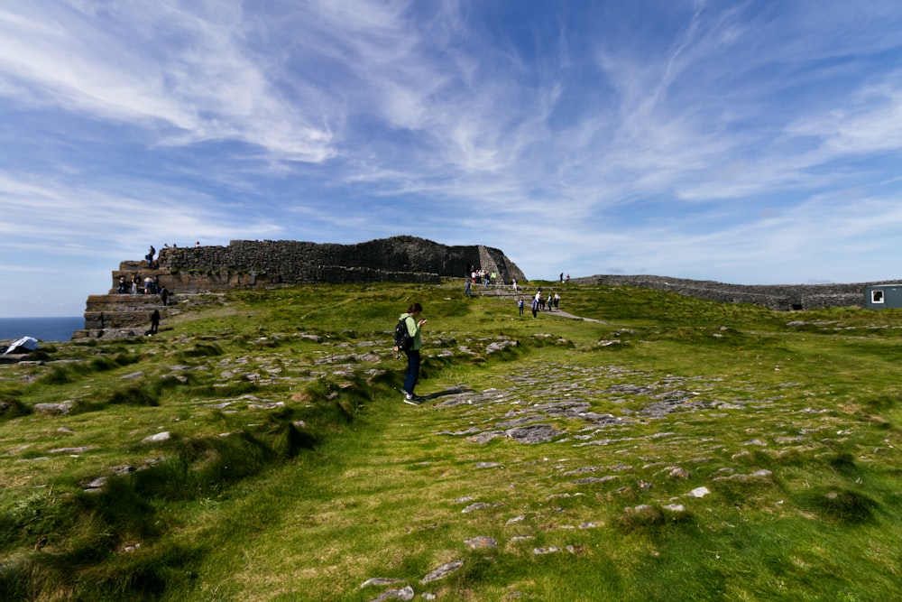 a group of people walking on a grassy hill by a body of water